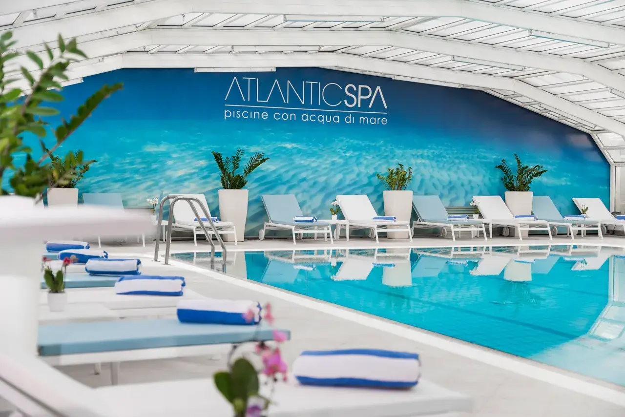 Rilassati nei bagni Riccione con piscina, un'oasi di benessere con lettini e teli blu.