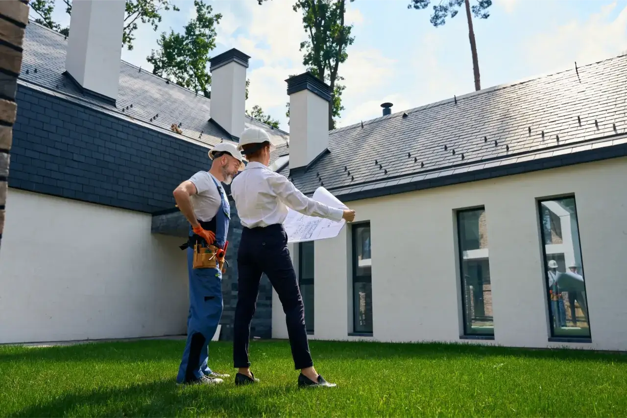Architekt i budowlaniec omawiają plany domu. Czy można mieszkać w domu bez odbioru? To pytanie, na które odpowiedź znajdą, analizując projekt.