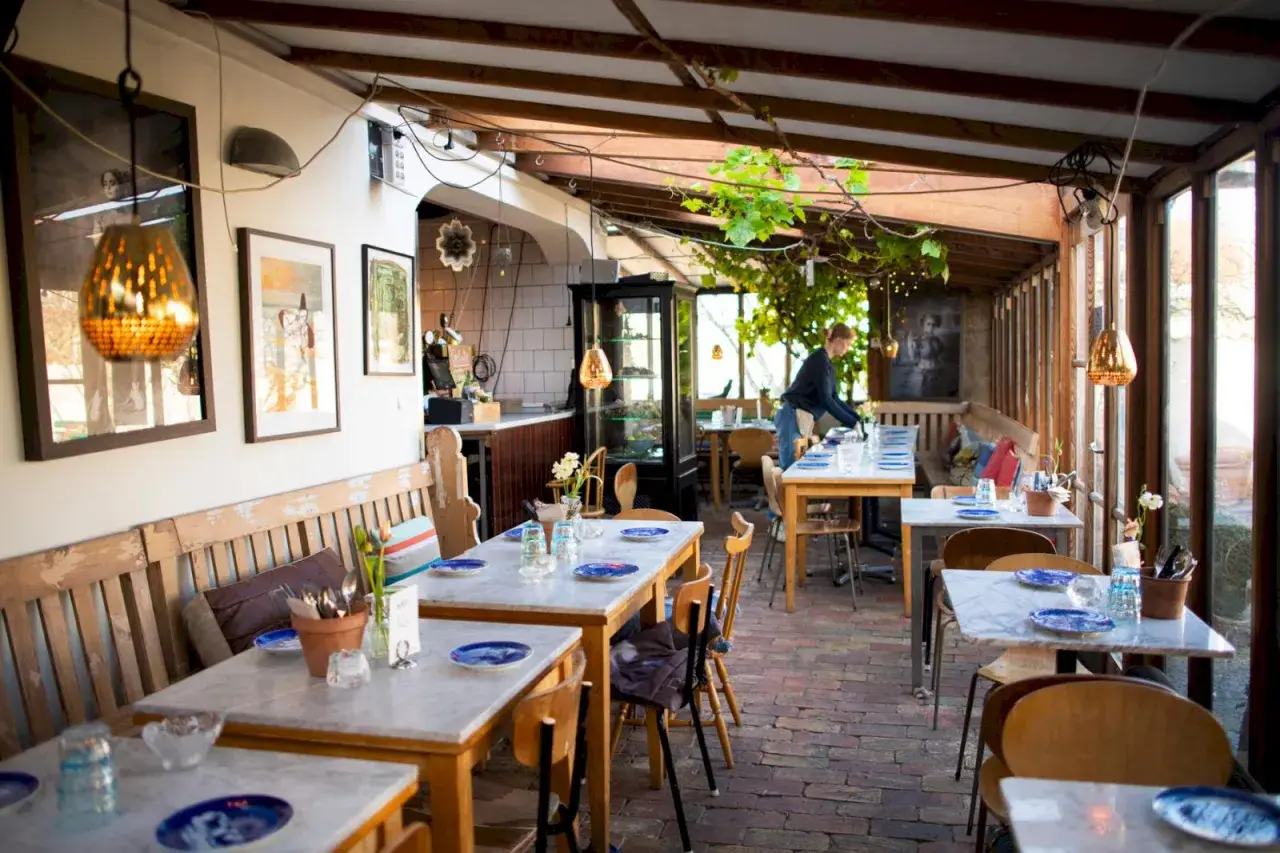 Mysig vinterträdgård med rustika bänkar och marmorbord, en av många annorlunda restauranger i Skåne.