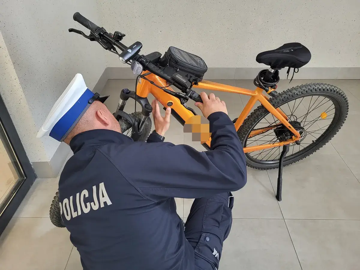 Policjant sprawdza, czy na rower elektryczny trzeba mieć prawo jazdy. Pomarańczowy rower z sakwą na kierownicy.