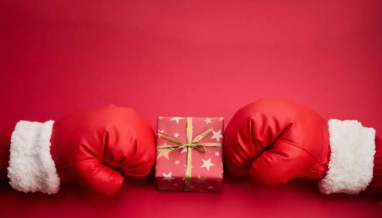 Rękawice bokserskie w świątecznym stylu otaczają prezent. Czy to zapowiedź, boxing day co to znaczy?