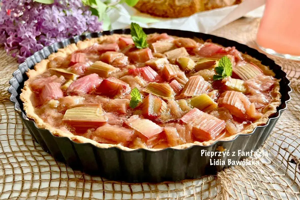 Pyszna tarta z rabarbarem, udekorowana listkami mięty, kusi swoim wyglądem.