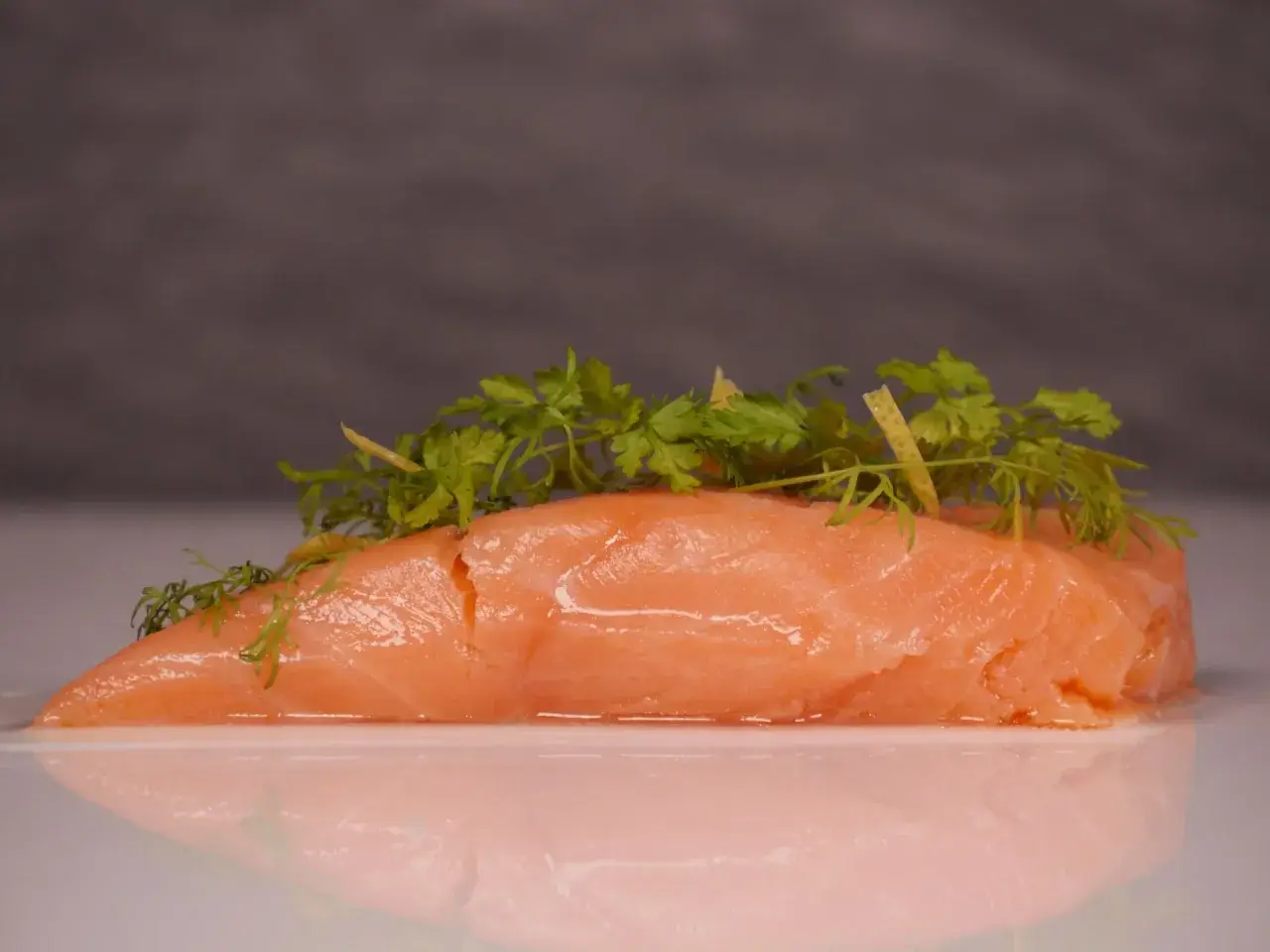 Zartes Lachsfilet, sous vide gegart, mit frischen Kräutern und Zitronenzesten garniert.