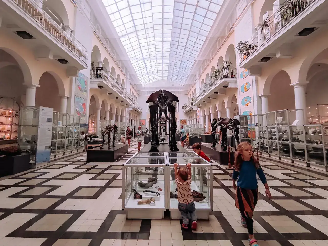 Dzieci zwiedzają Muzeum Ewolucji PAN, jedno z najciekawszych muzeów w Warszawie, podziwiając szkielet mamuta.