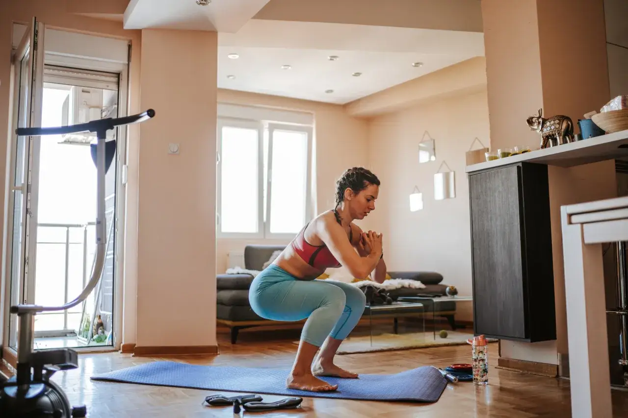 Frau macht Kniebeugen auf einer Matte, ein Beispiel für effektives **Eigengewicht Training** zu Hause.