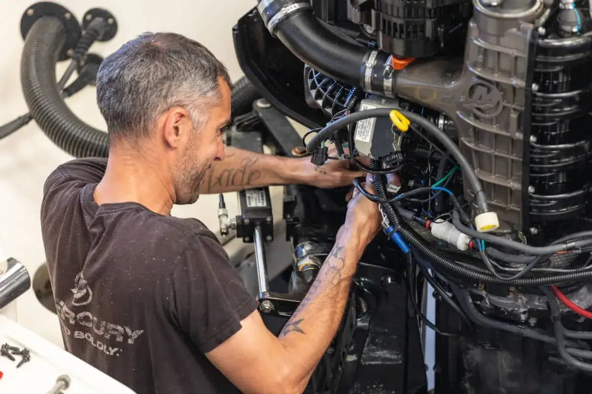 Un mécanicien s'affaire sur un moteur électrique, câbles et tuyaux visibles. Il sait comment tester un moteur électrique pour assurer son bon fonctionnement.