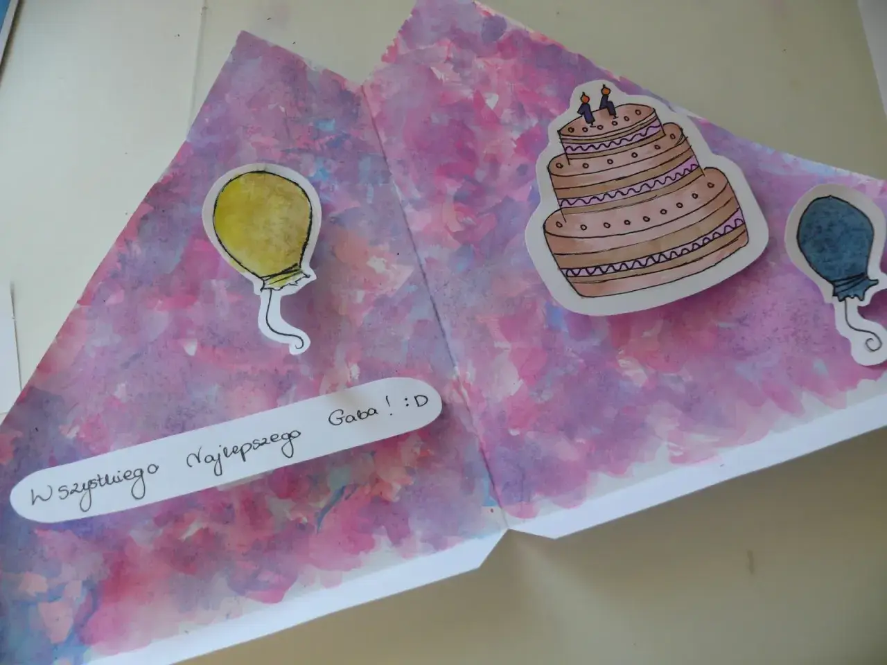 Kolorowa kartka urodzinowa DIY z namalowanym tortem i balonami. Napis "Wszystkiego Najlepszego Gaba! :D" dodaje osobistego charakteru.
