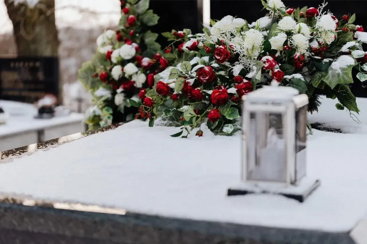 Wieniec dla taty: czerwone róże i białe kwiaty na śniegu, obok lampion.