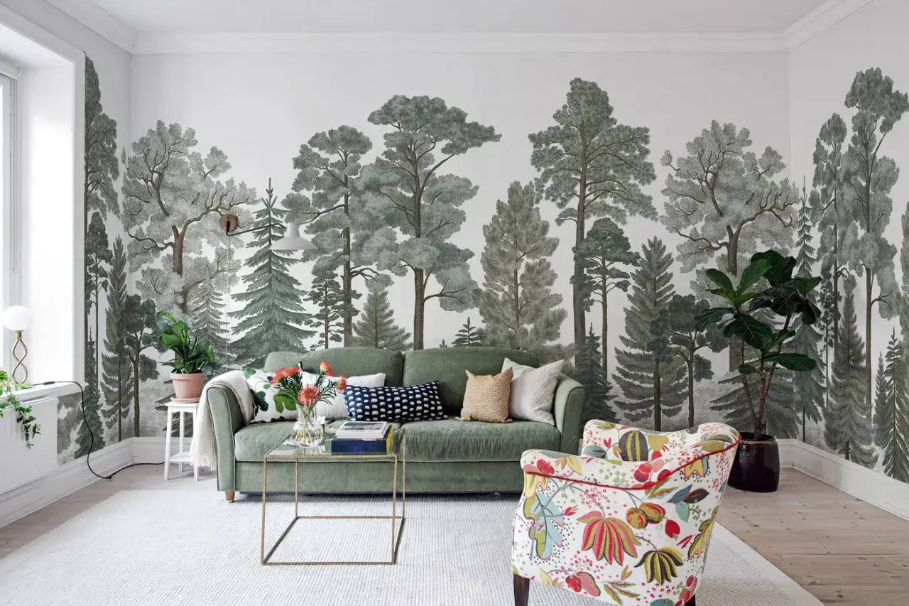 Mural w mieszkaniu z motywem lasu, zielona sofa i kolorowy fotel tworzą przytulną przestrzeń.
