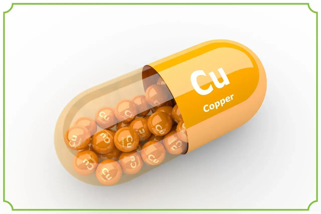 Pomarańczowa kapsułka z wysypującymi się z niej kulkami z napisem "Cu Copper". Suplement diety.