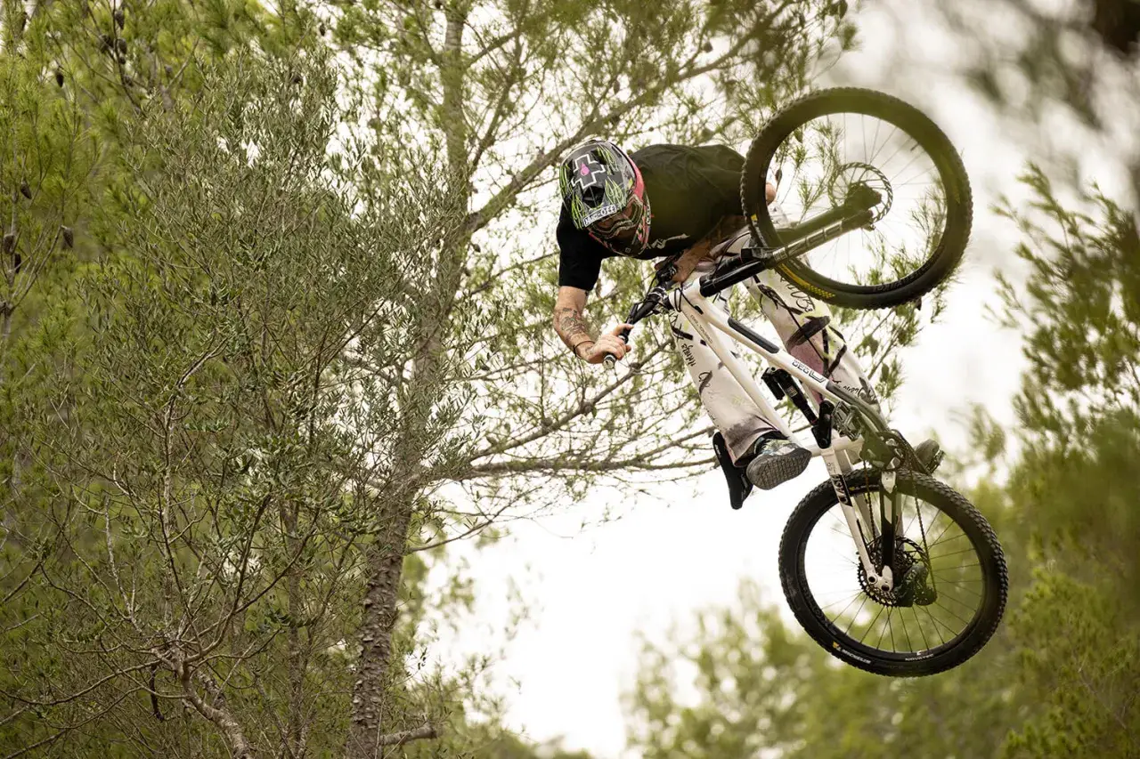 Tomas Lemoine fliegt mit seinem Mountainbike durch die Luft, umgeben von Bäumen.