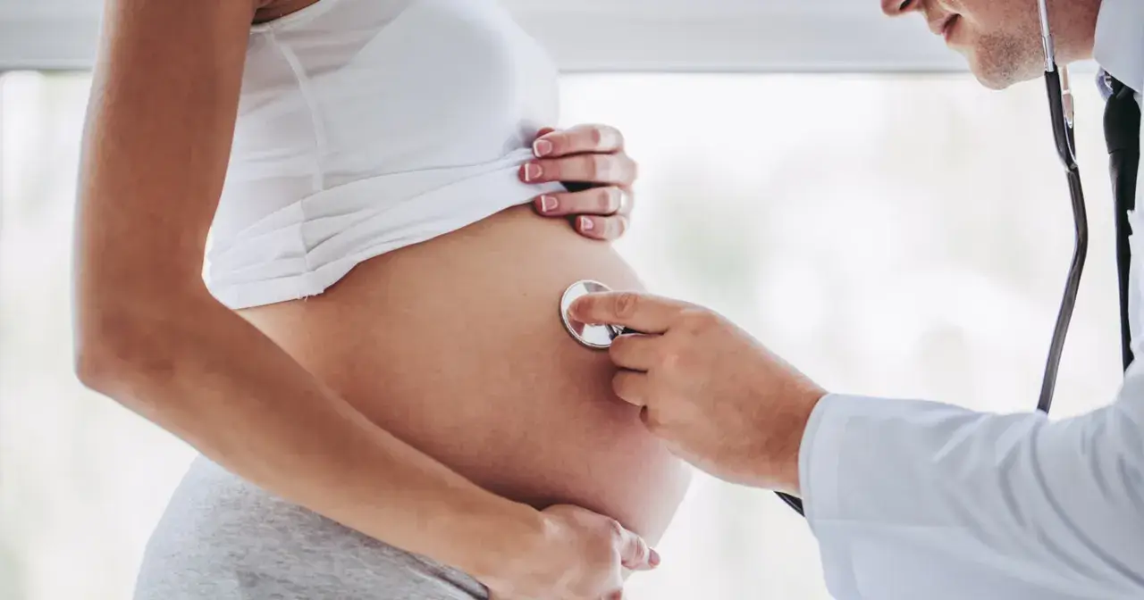 Lekarz osłuchuje brzuch ciężarnej kobiety, która jest w 24 tygodniu ciąży.