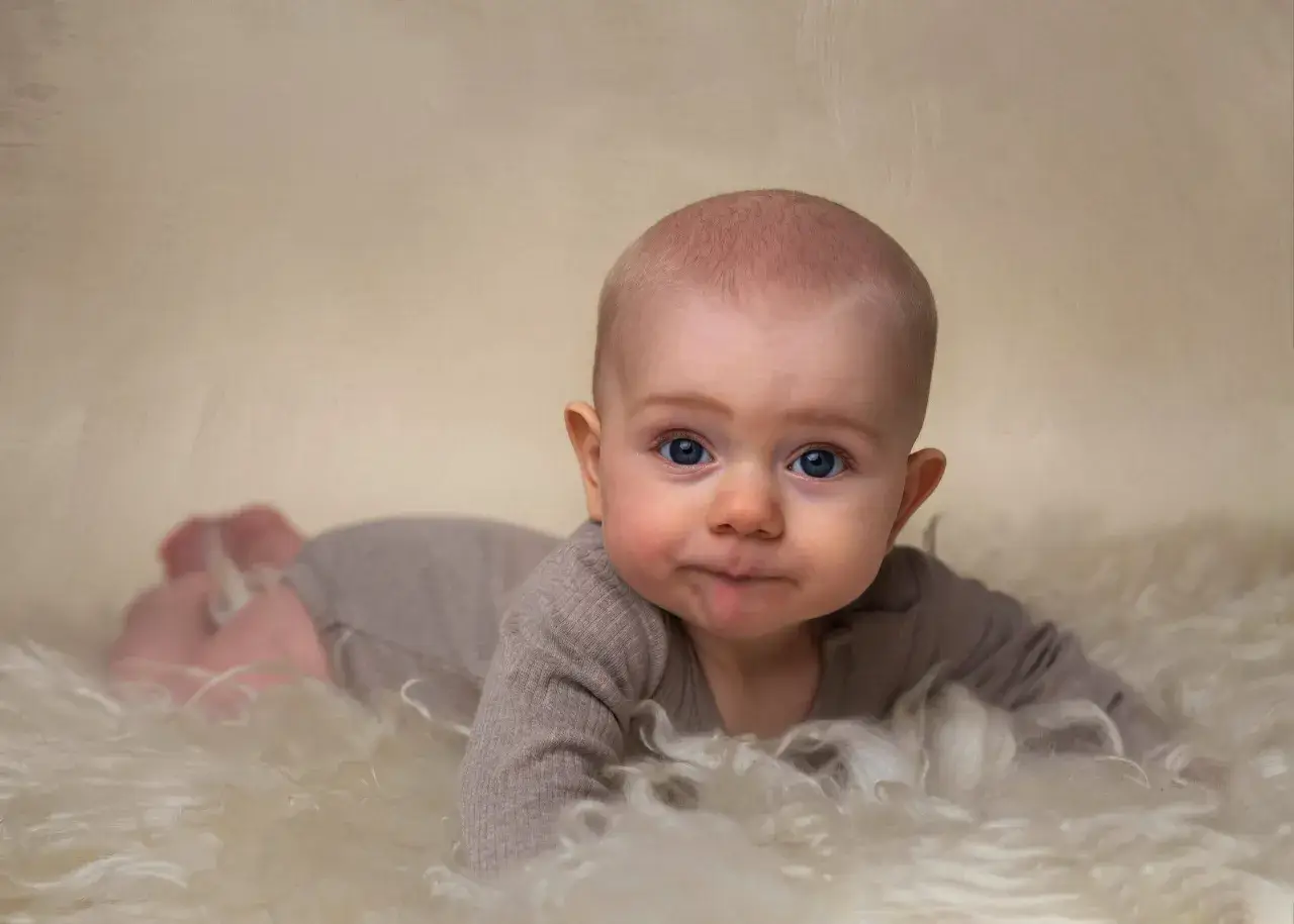 Niebieskooki maluch na miękkim futerku, ćwiczy pełzanie, kiedy tylko ma okazję.