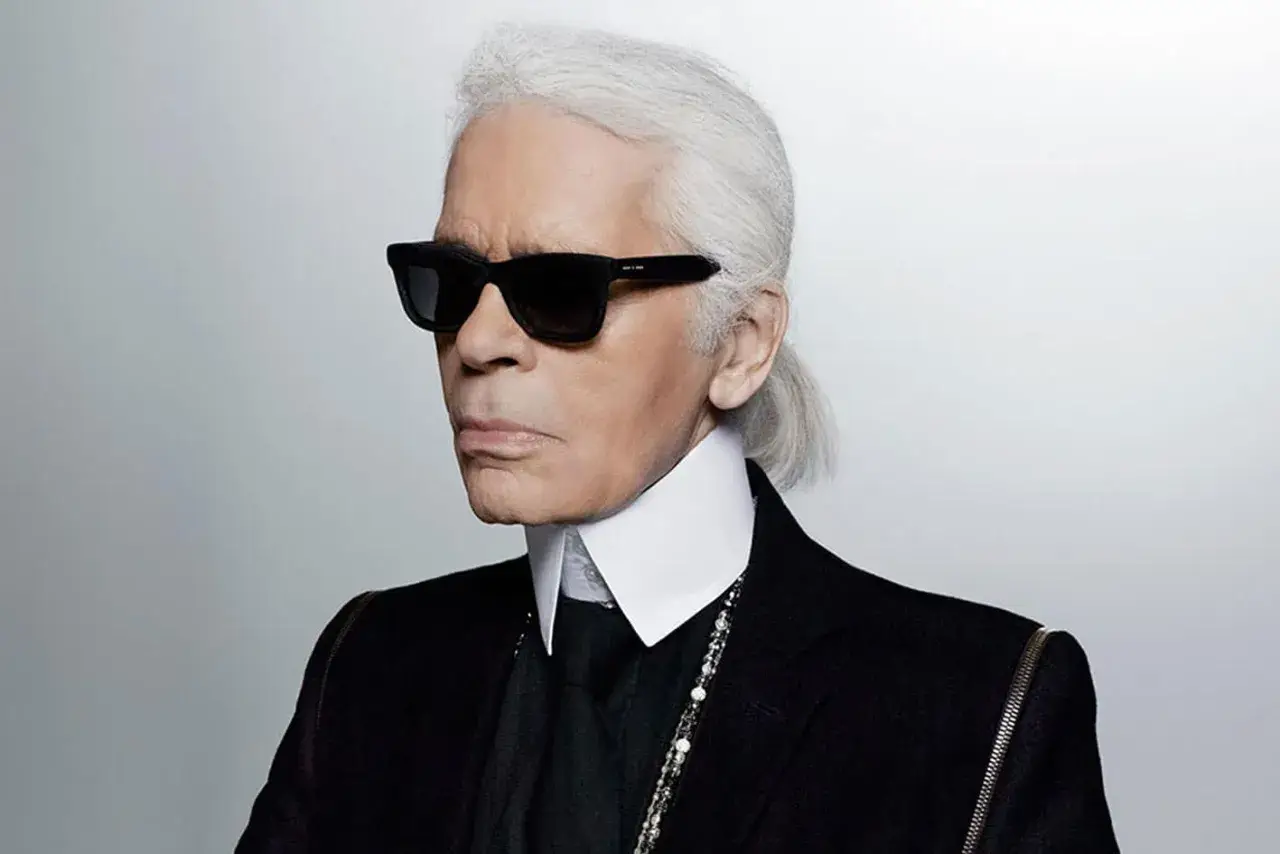 Ikona stylu, Karl Lagerfeld, w czarnym garniturze i okularach. Kto to? Ikona mody.