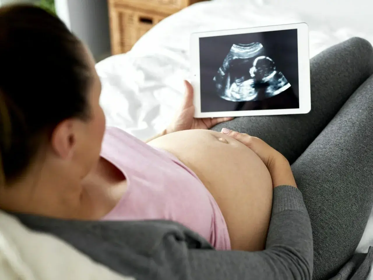 Kobieta w ciąży ogląda na tablecie zdjęcie USG. To jej badania prenatalne w 3 trymestrze.