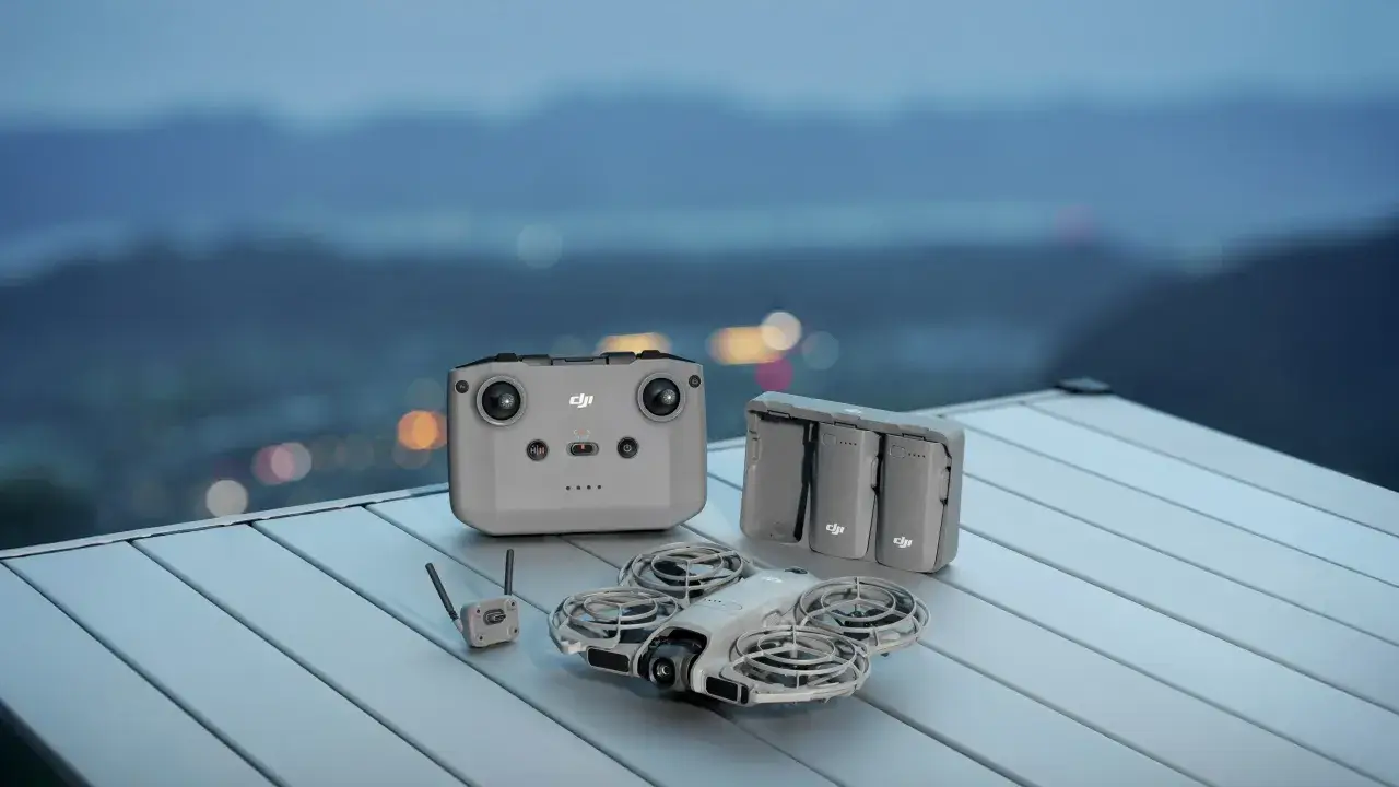 DJI Mini 2 z pilotem, bateriami i modułem do śledzenia obiektu, gotowy do lotu nad nocnym miastem.