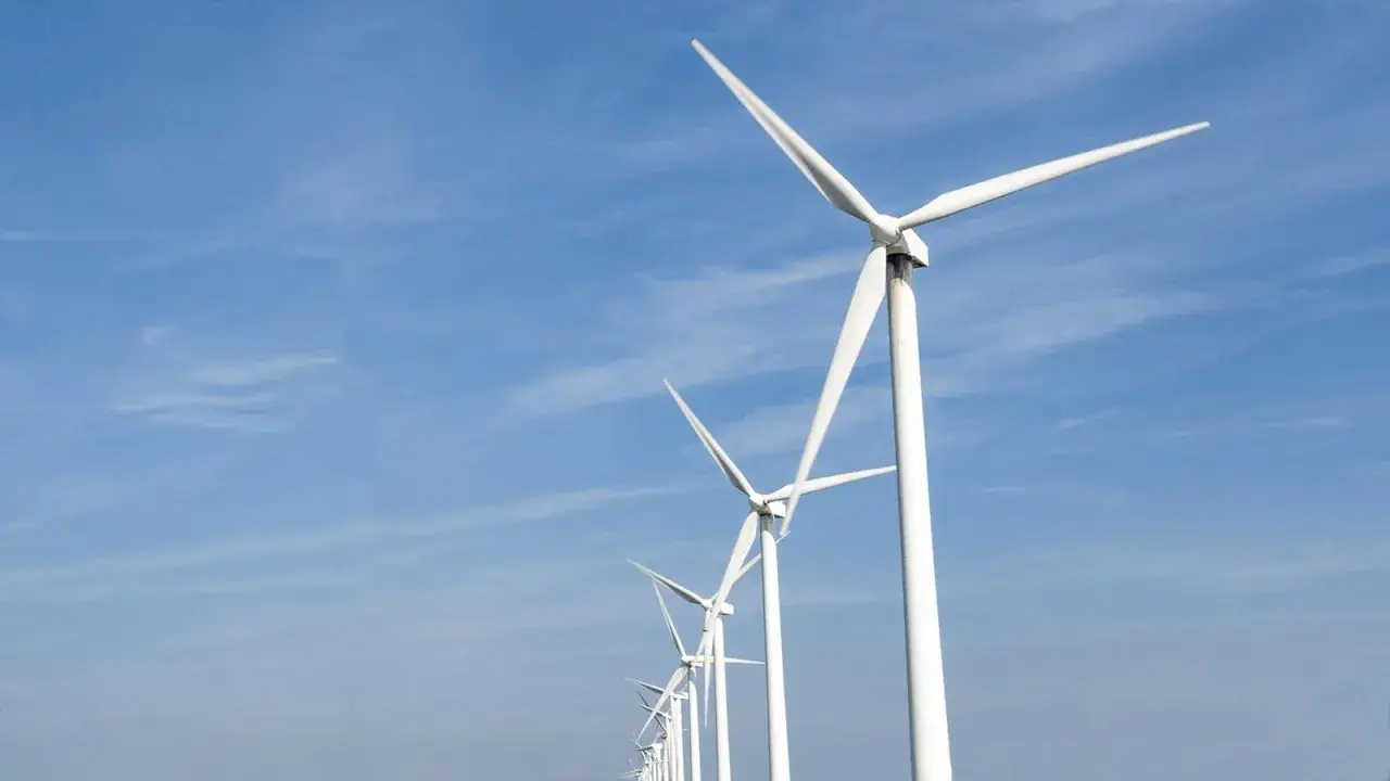 Reihe von Windrädern unter blauem Himmel, ein Symbol für Frankreichs Engagement für erneuerbare Energien.