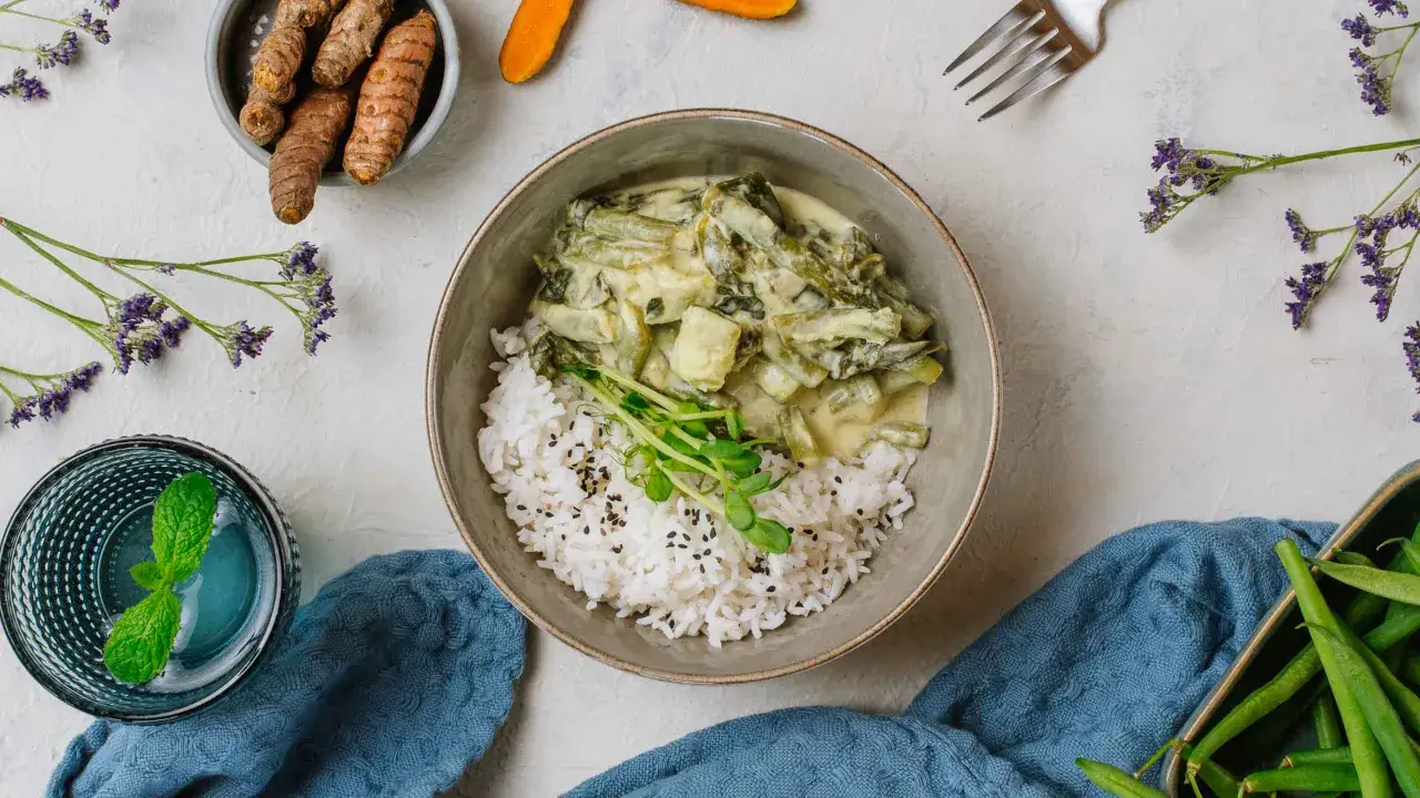 Zielony curry z fasolką szparagową i ryżem, idealne do diety 3000 kcal. Obok świeży imbir i napój z miętą.