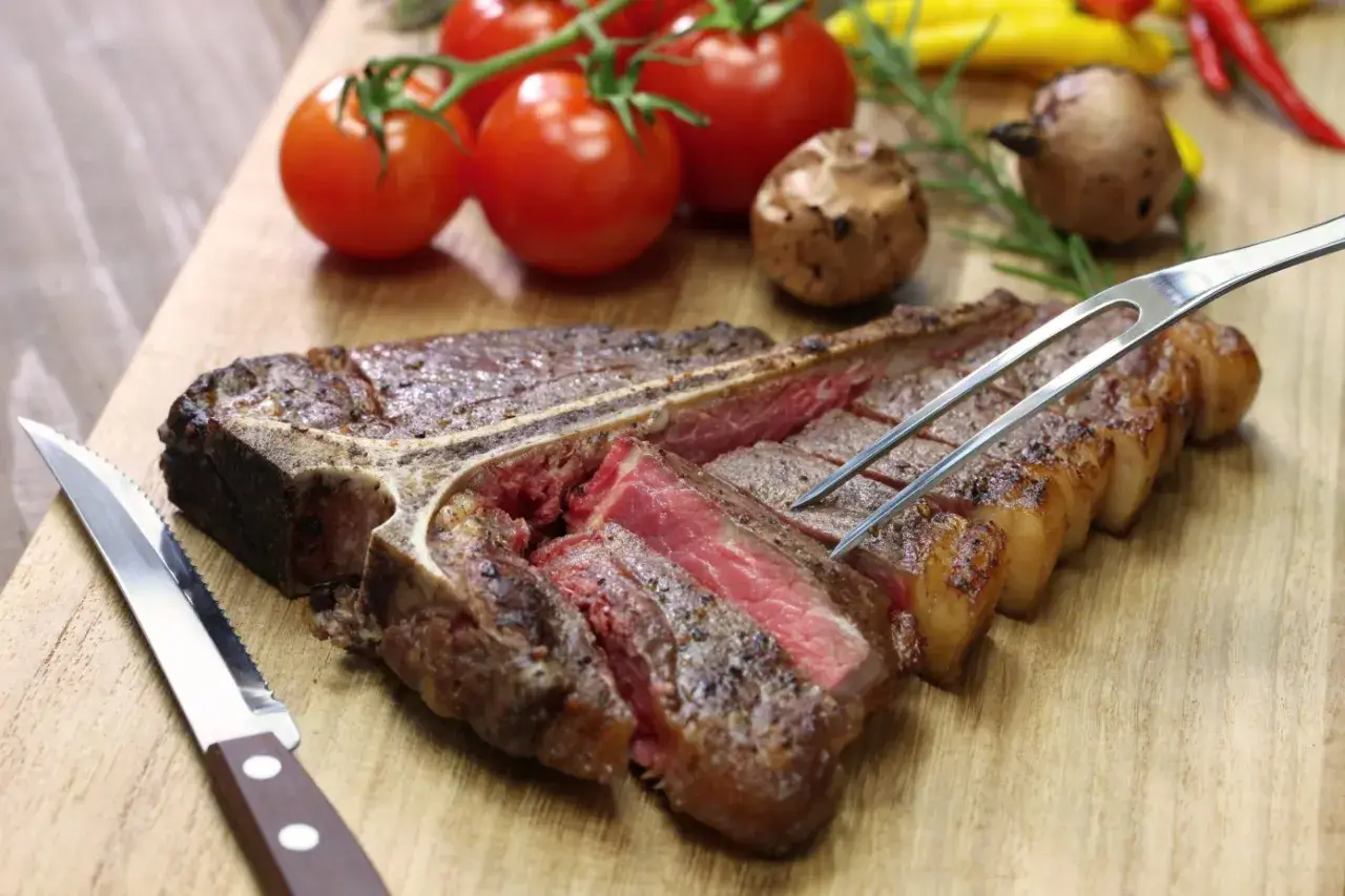 Una succulenta bistecca alla fiorentina, tagliata e pronta per essere gustata. Perfetta per scoprire dove mangiare la fiorentina a Firenze.