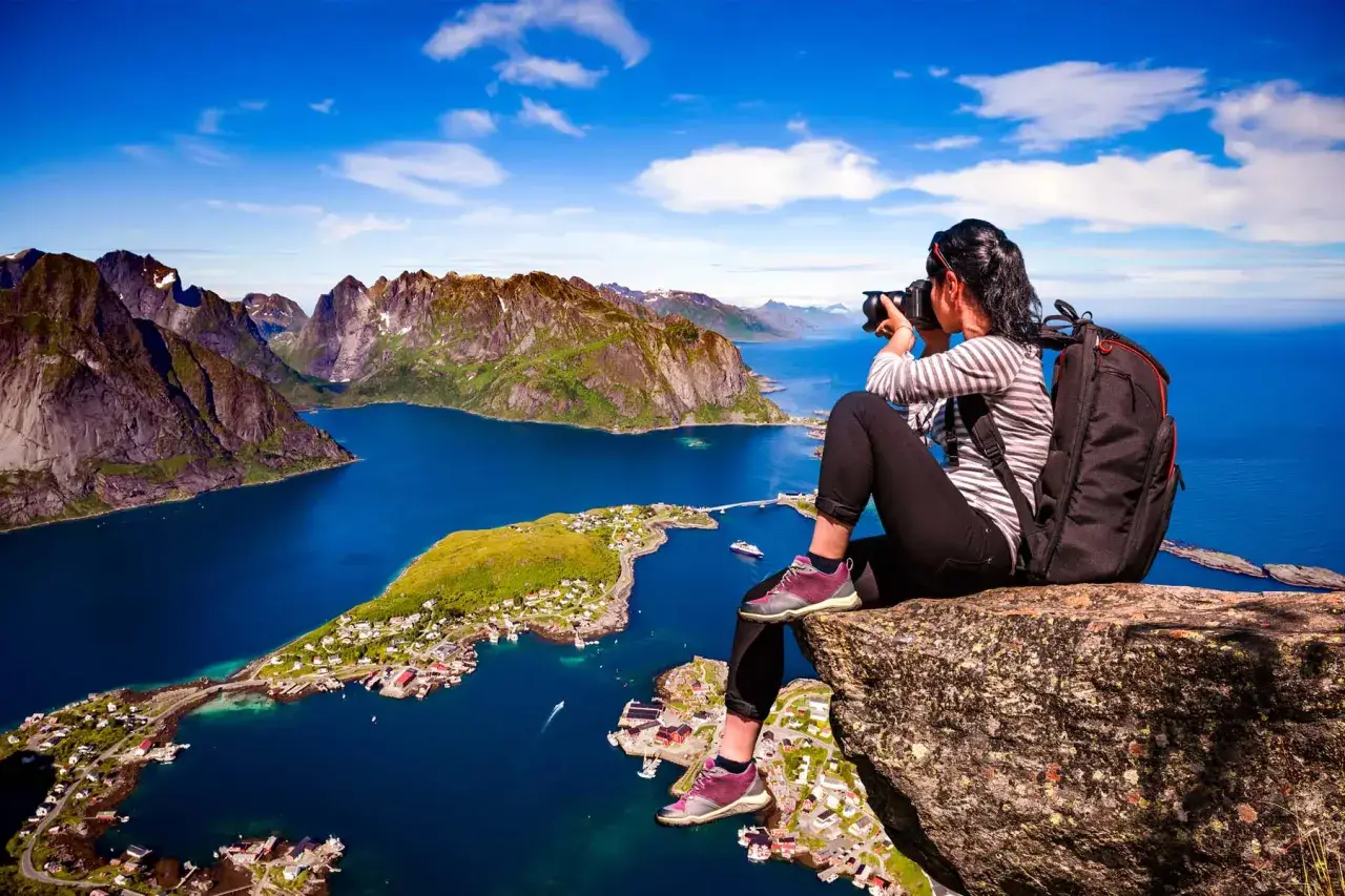 En fotograf fångar de dramatiska vyerna över Lofoten sevärdheter, med branta berg och en idyllisk by vid det blå havet.