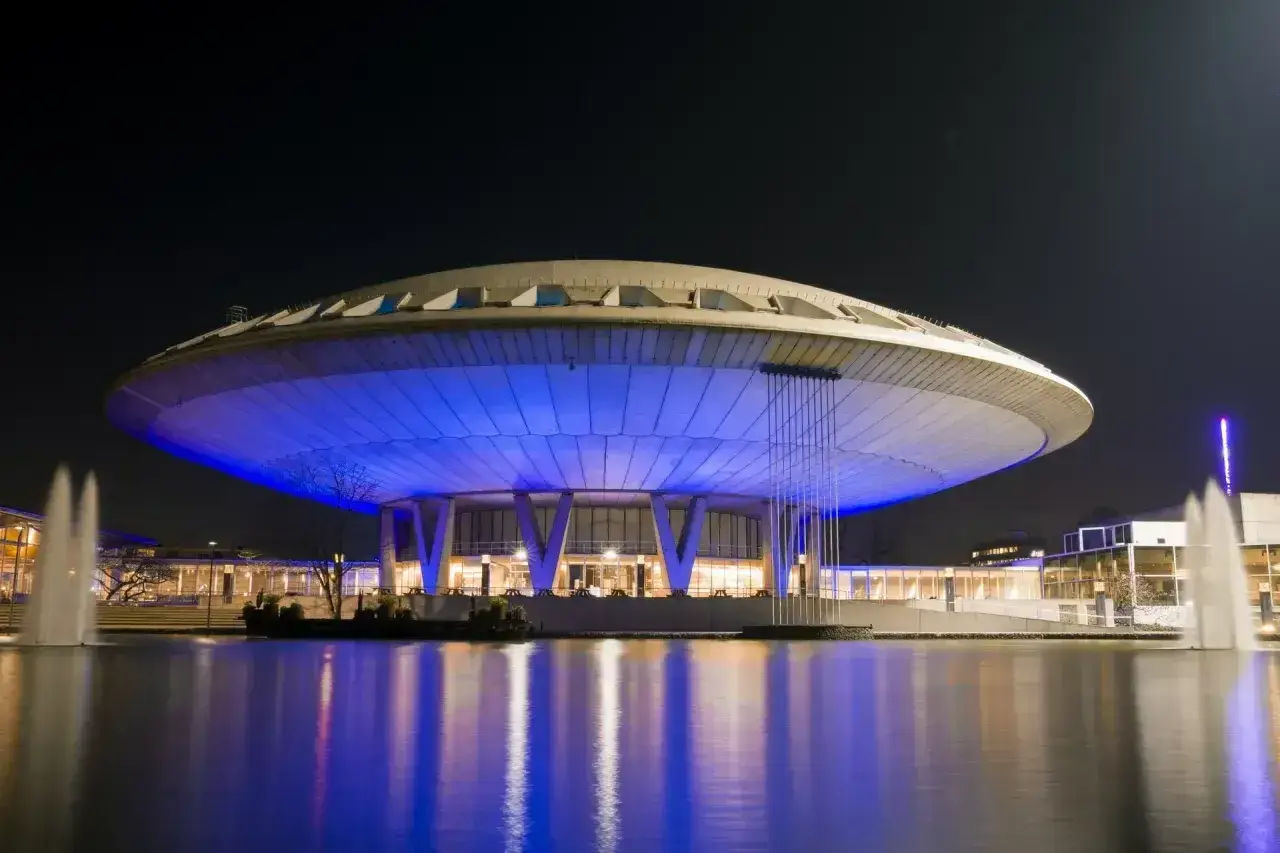 Futurystyczny budynek w Eindhoven, oświetlony niebieskim światłem, z fontannami w stawie. Jedna z głównych eindhoven atrakcji.