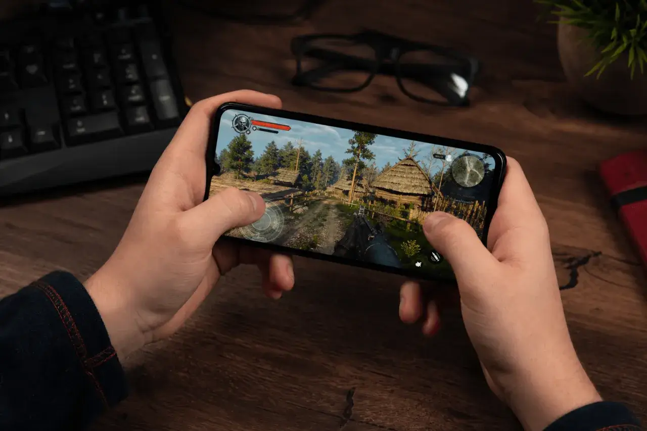 Ręce trzymają smartfon z grą akcji w stylu fantasy. To jedna z najlepszych gier mobilnych.
