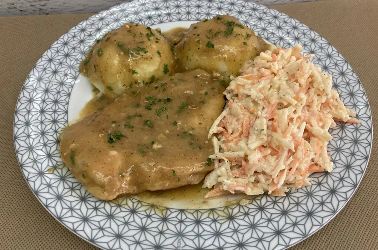 Pyszna pierś z kurczaka w sosie własnym, podana z purée ziemniaczanym i surówką z marchewki i kapusty.