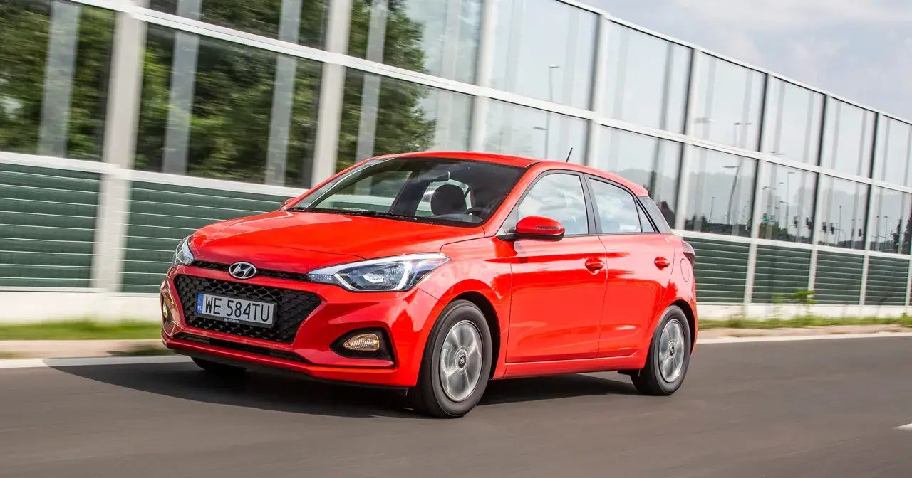 Czerwony Hyundai i20 1.2 benzyna w ruchu, z nowoczesną atrapą chłodnicy i światłami.