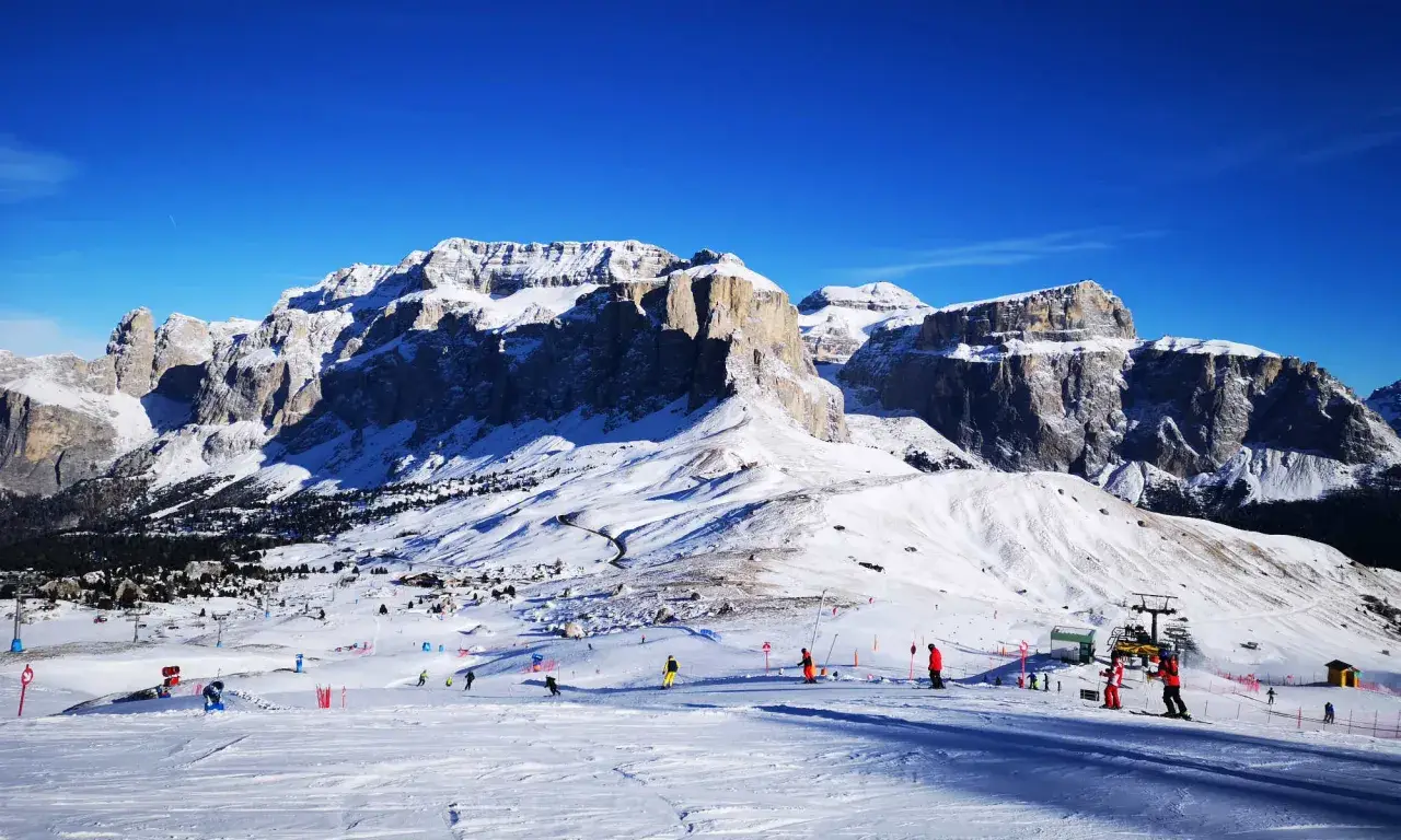 Piste innevate e maestose vette per decidere dove andare a sciare in Trentino. Sciatori e impianti di risalita animano il paesaggio.