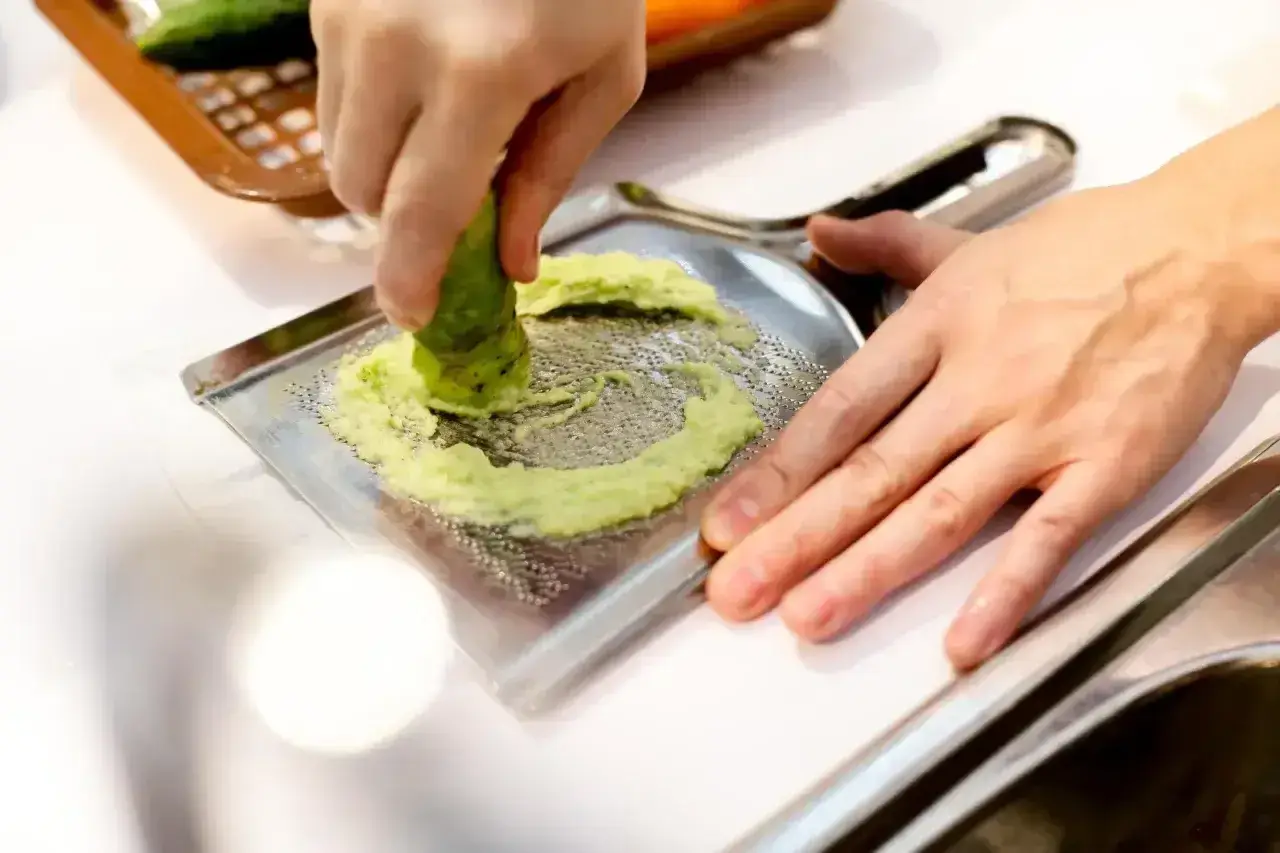 Ręka trze korzeń wasabi o tarkę. To właśnie tak powstaje świeże wasabi, które dodaje ostrości potrawom.