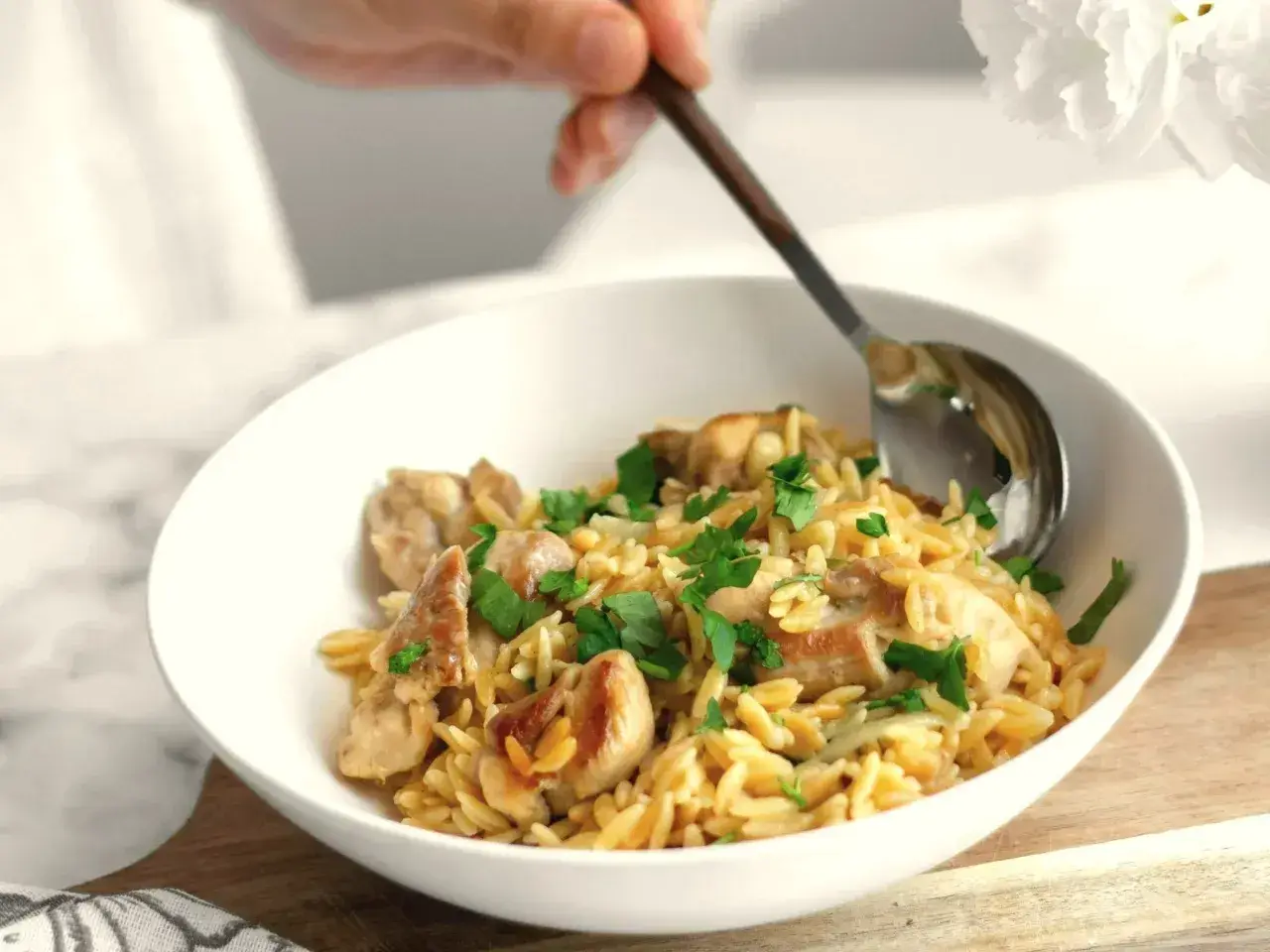 Szybki obiad z makaronem orzo i kurczakiem, posypany natką pietruszki. Idealny na szybki posiłek.