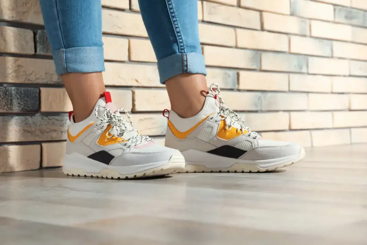 Białe sneakersy z żółtymi i czarnymi akcentami, idealne do jeansów. Czy to HOFF buty? Co to za firma?