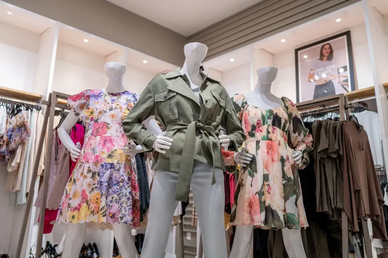 Manekiny w sukienkach w kwiaty i zielonej kurtce. To styl marki Scotch & Soda, znanej z kolorowych, letnich ubrań.