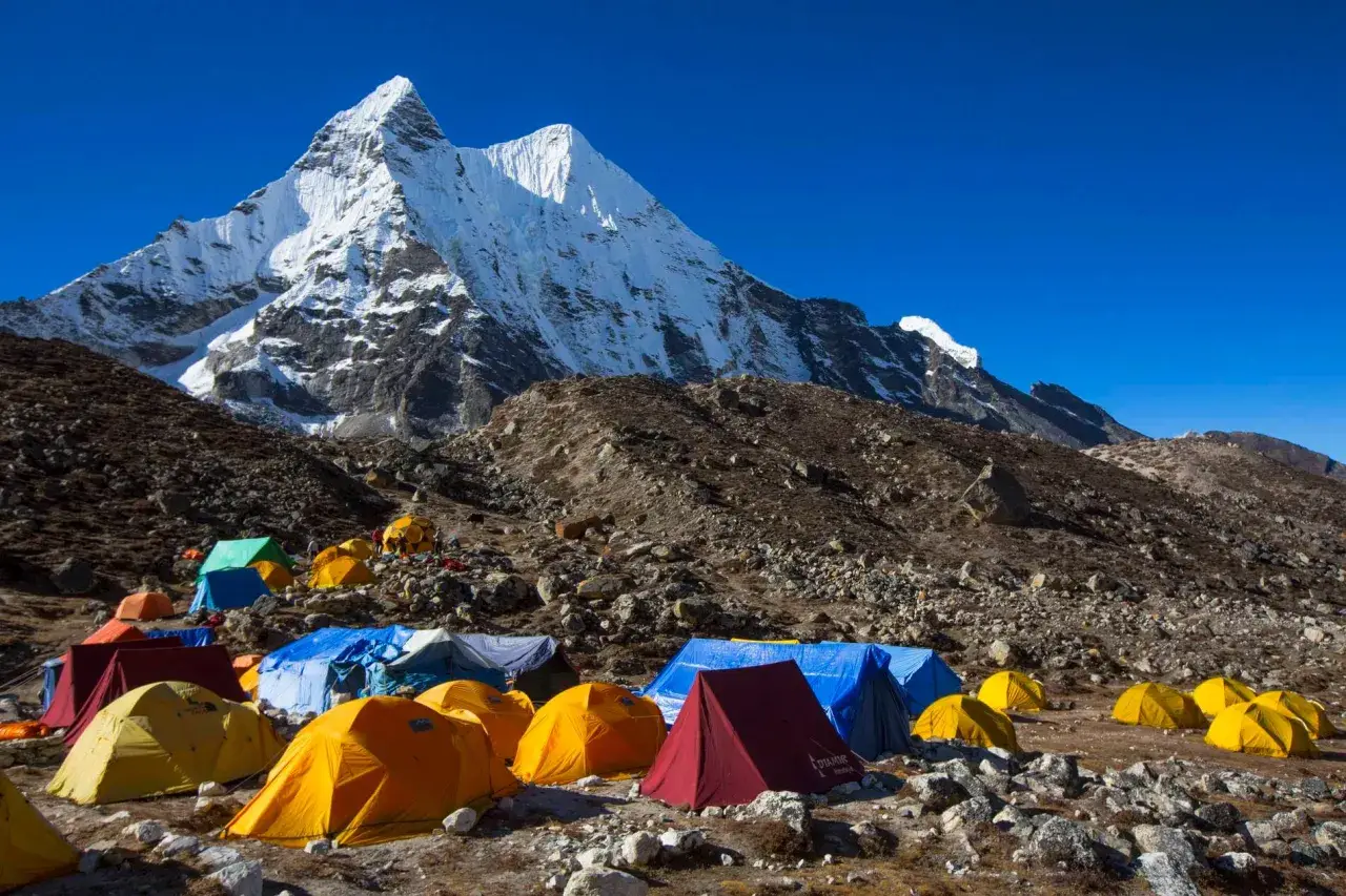 Obóz pod majestatycznym szczytem Karakorum. Kolorowe namioty rozstawione na kamienistym zboczu, gotowe na przyjęcie alpinistów.