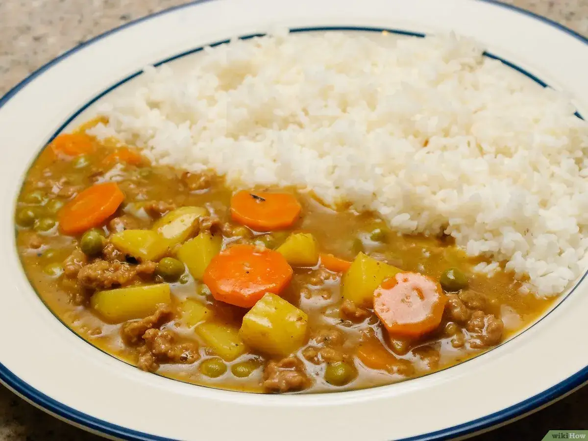 Un plat de riz blanc servi avec un curry japonais savoureux, garni de morceaux de carottes, de pommes de terre et de petits pois.