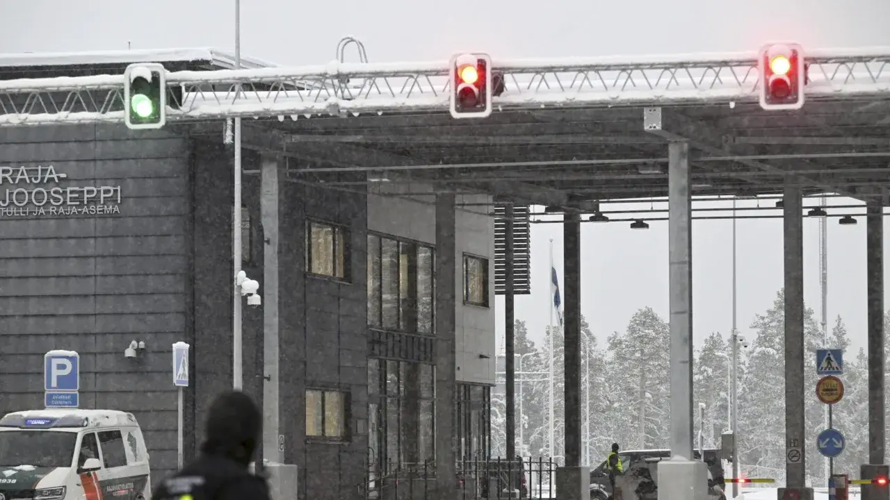 Grön trafiksignal vid gränsövergången Joensuu, Finland. Snö faller över byggnaden och träden. En polisbil syns. Gränsen mellan Ryssland och Finland är stängd.