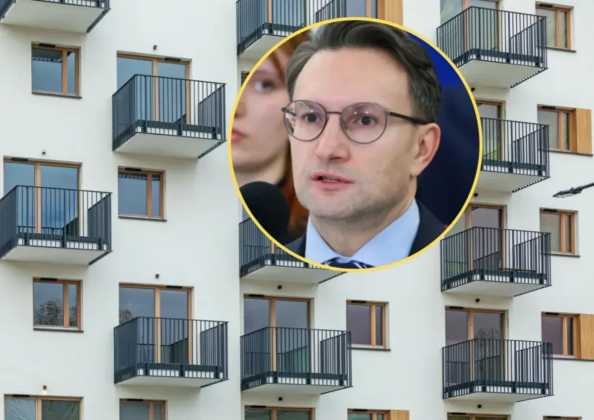 Mężczyzna w okularach przemawia na tle nowoczesnego bloku z balkonami, dyskutując o problemach najmu krótkoterminowego.