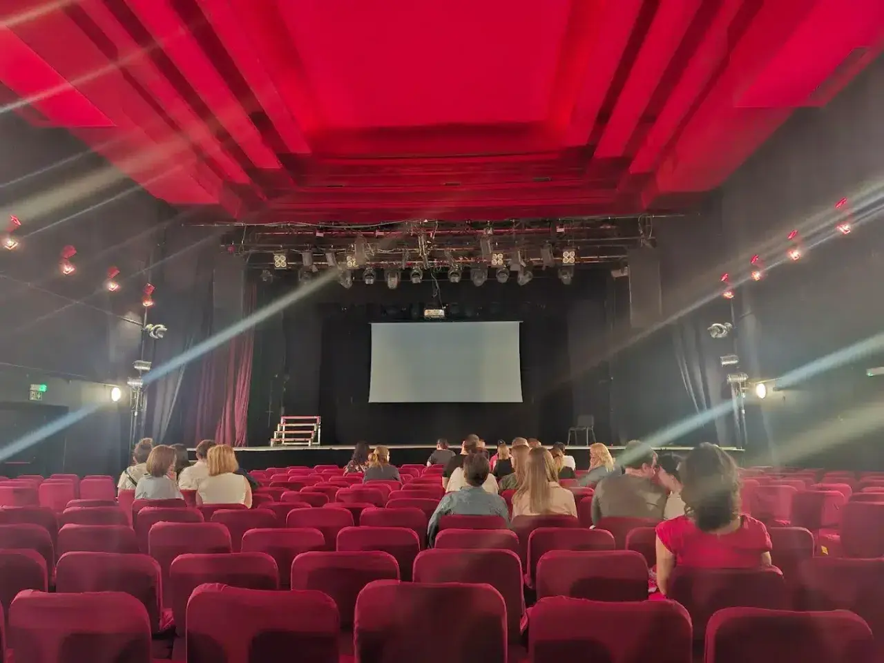 Widownia w Teatrze Palladium w Warszawie. Czerwone fotele i scena z ekranem czekają na widzów.