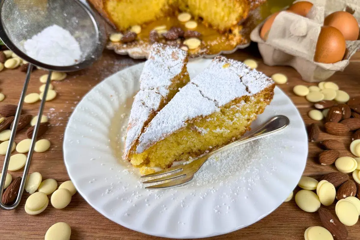 Fette di caprese al limone spolverate di zucchero a velo, con mandorle e gocce di cioccolato bianco.