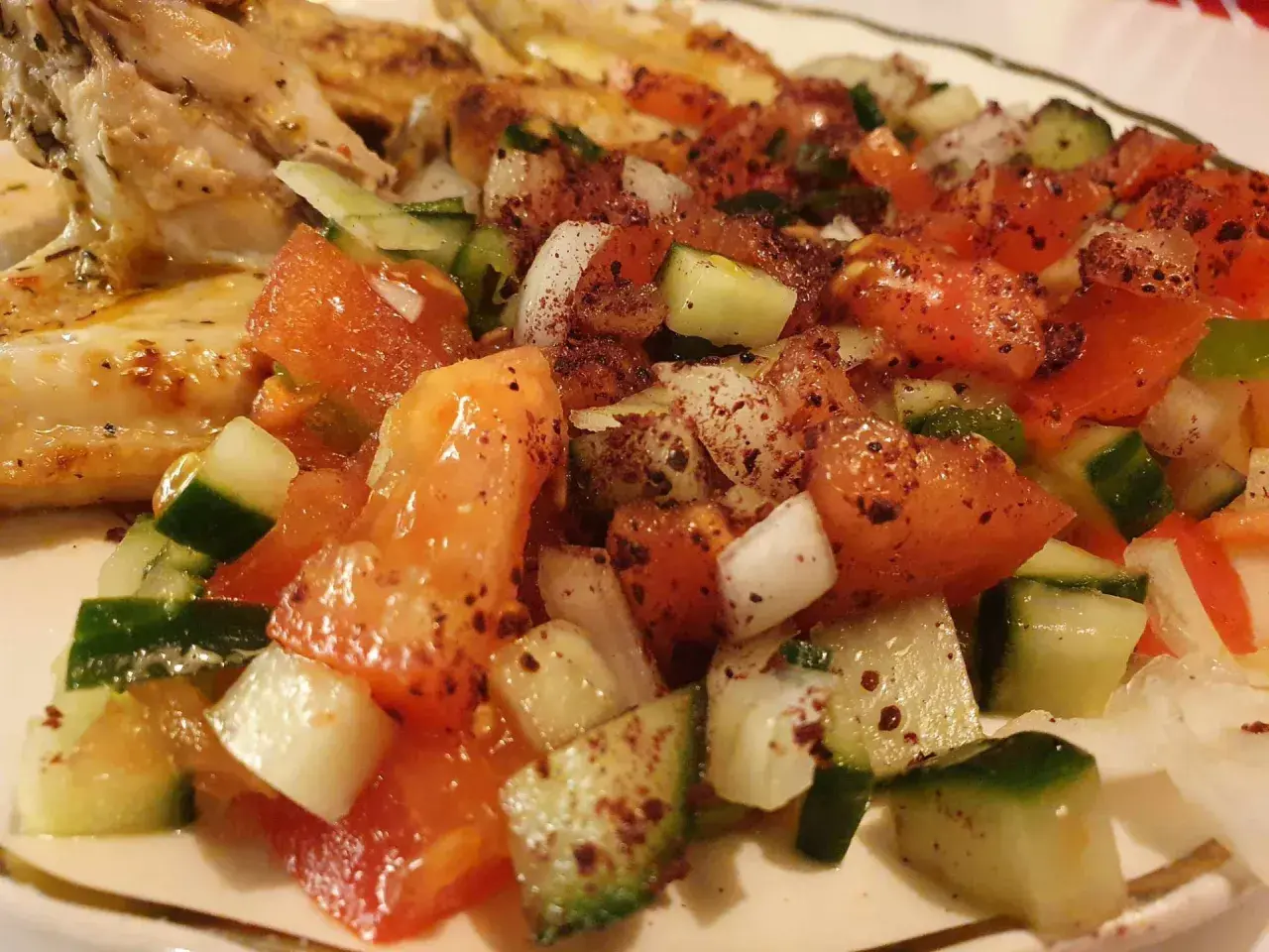 En saftig coban salata med tomater, gurka och lök, kryddad med sumak, serveras bredvid grillad kyckling.