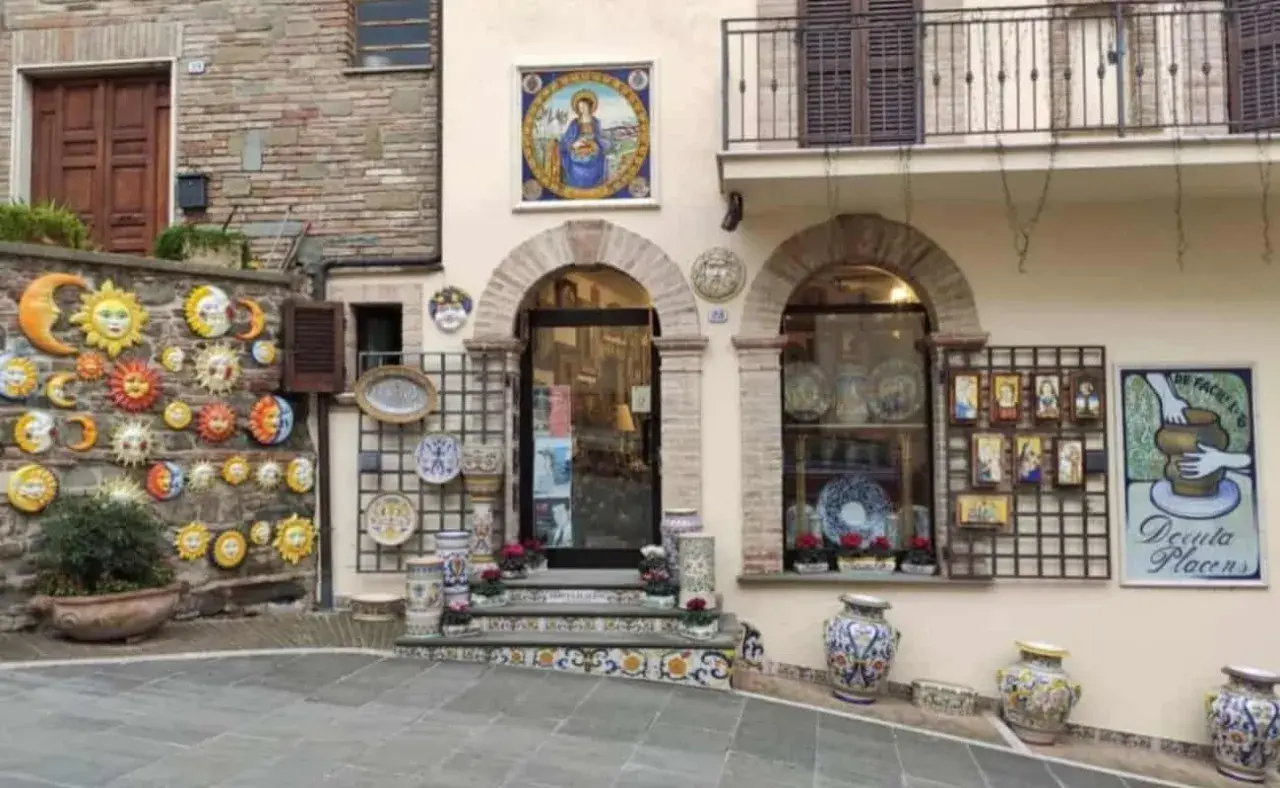 Deruta cosa vedere: bottega di ceramiche con soli, lune, vasi e decorazioni murali.