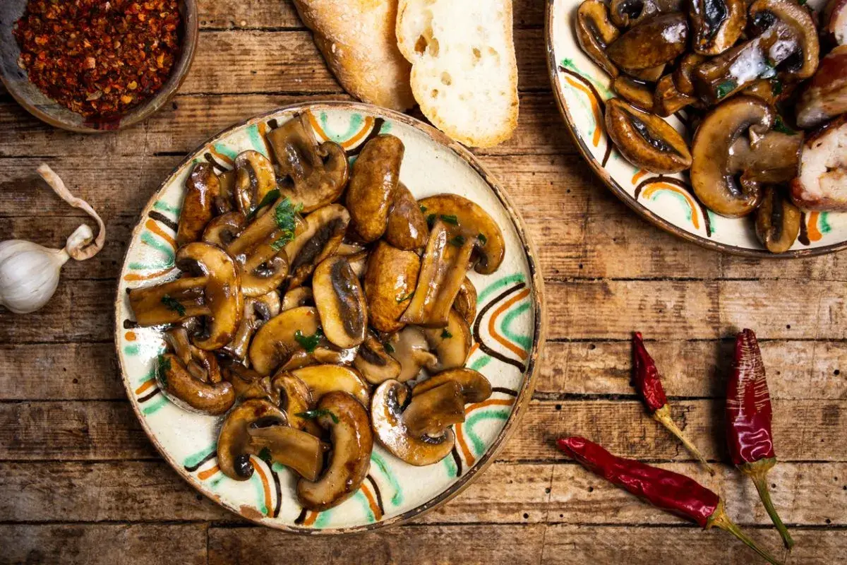 Plato de setas a la plancha con ajo, pan y guindillas secas. Un delicioso aperitivo rústico.