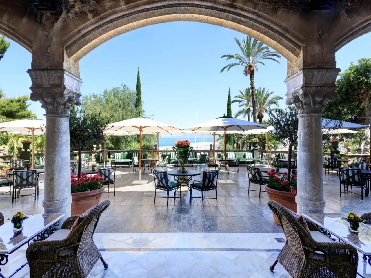 Terrazza con vista mare per un aperitivo a Palermo, tra palme e archi antichi.
