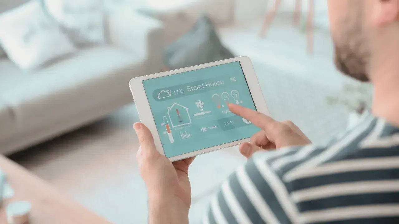Un hombre controla su hogar inteligente desde una tablet, un vistazo a la historia de la domótica.