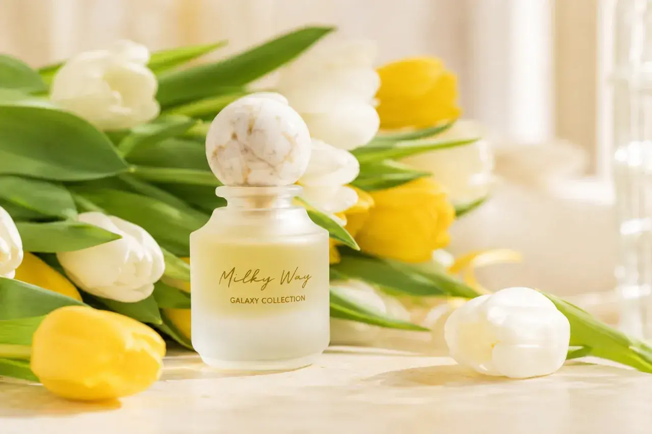 Eleganckie perfumy na prezent, otoczone bukietem białych i żółtych tulipanów. Czy to dobry omen, czy przesądy związane z podarunkiem?