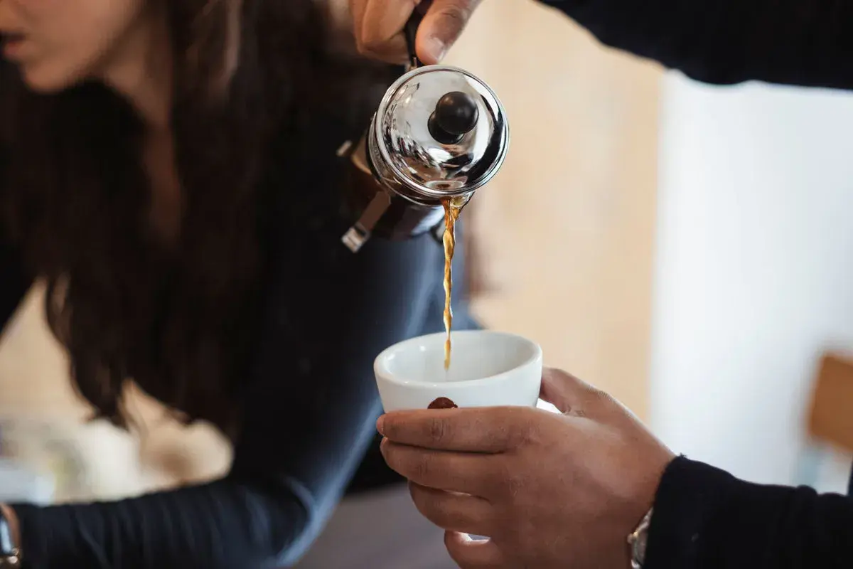 Eine French Press wird benutzt, um frisch gebrühten Filterkaffee in eine Tasse zu gießen.