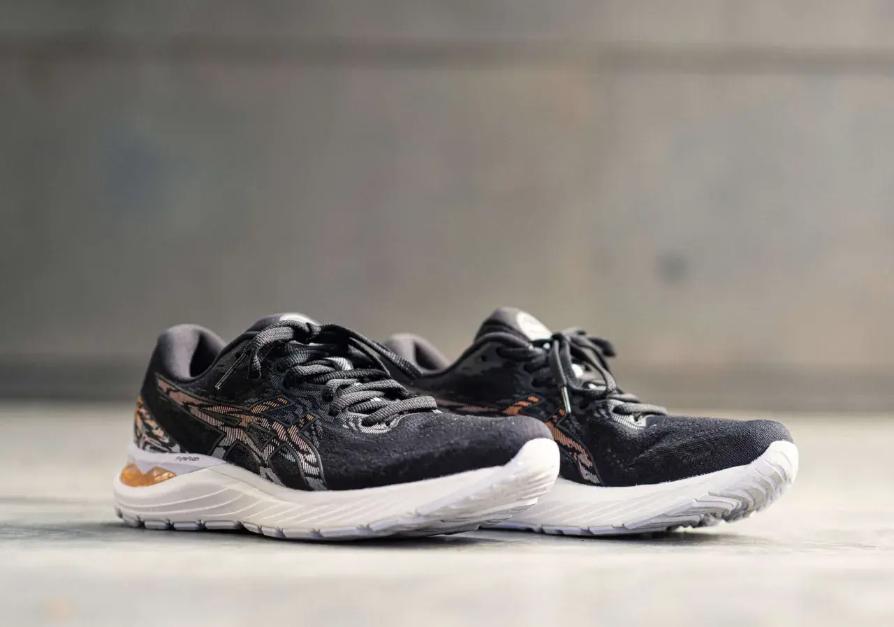 Scarpe da corsa Asics Gel Cumulus 23 nere con dettagli in bronzo e suola bianca, pronte per ogni avventura.