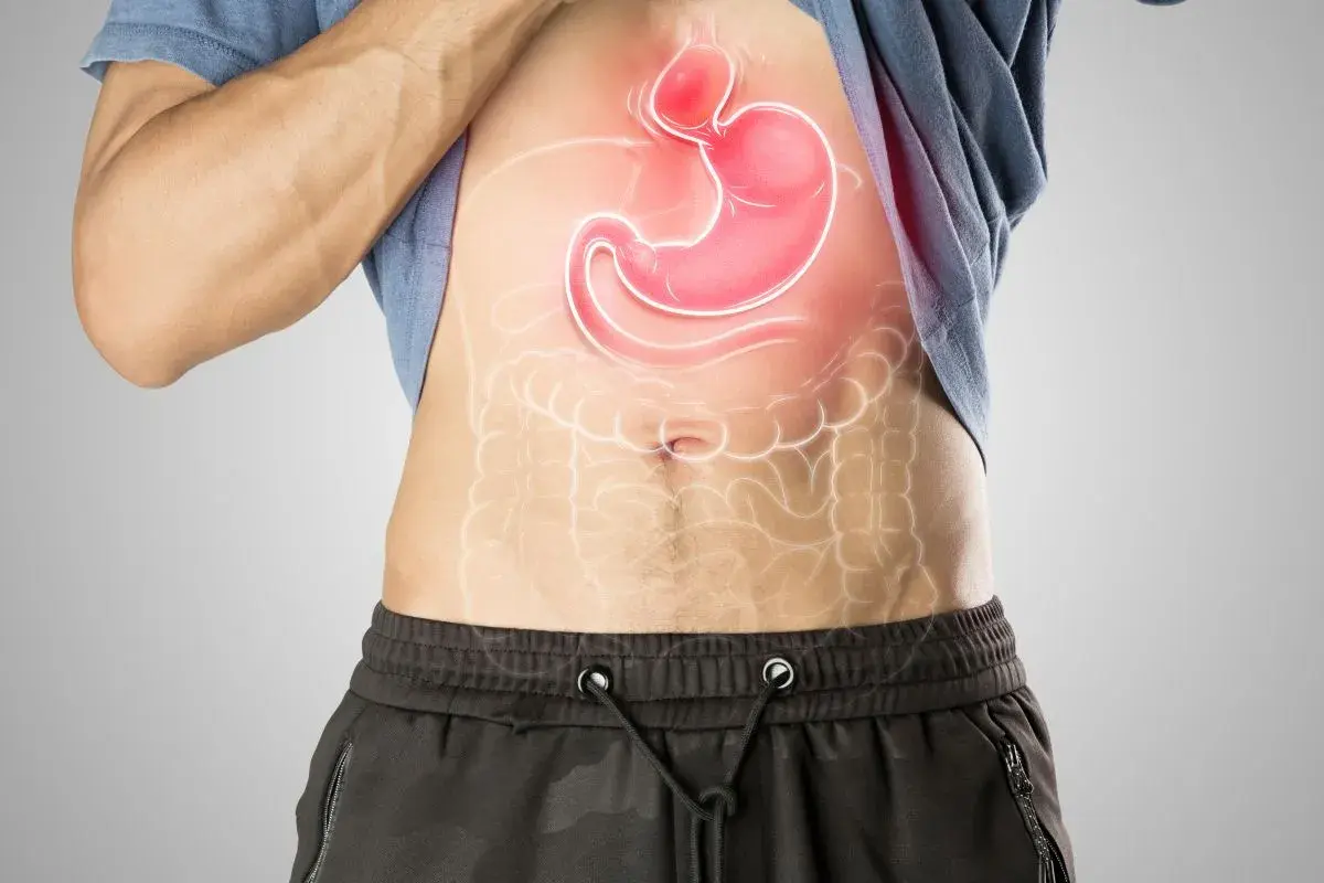 Uomo con stomaco evidenziato in rosso, che suggerisce fitte allo stomaco.