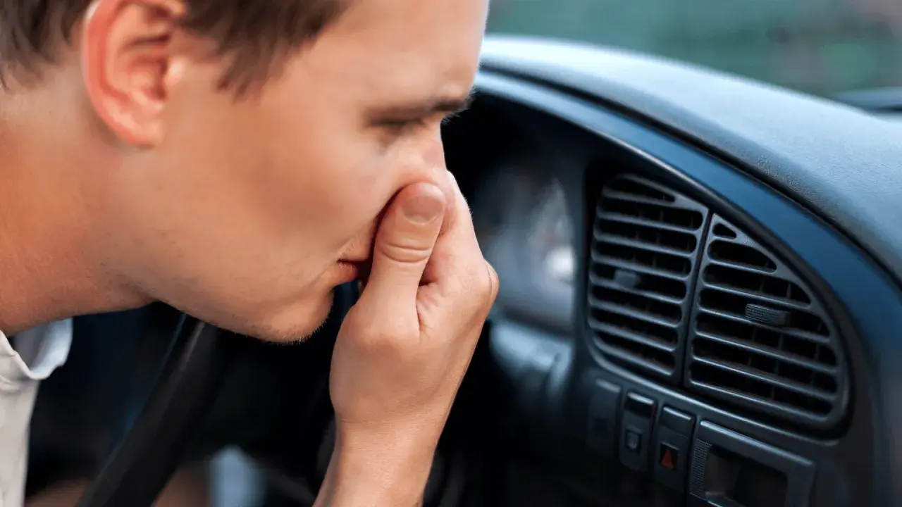 Man håller för näsan i bilen, en tydlig signal att det är dags att ta bort dålig lukt i bil.