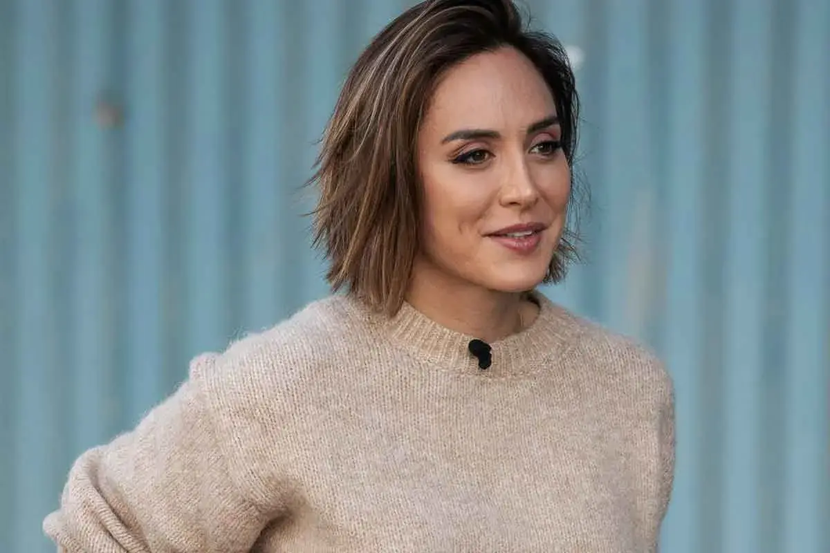 Mujer con un moderno corte pelo bob capas, luciendo un suéter beige y una sonrisa.
